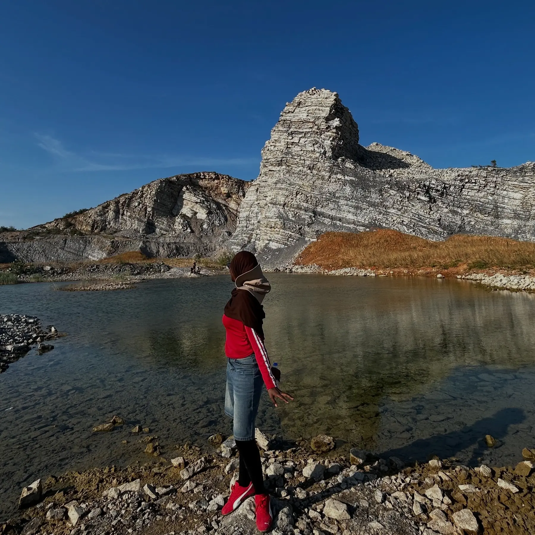 Amina in red by a mountain lake in China